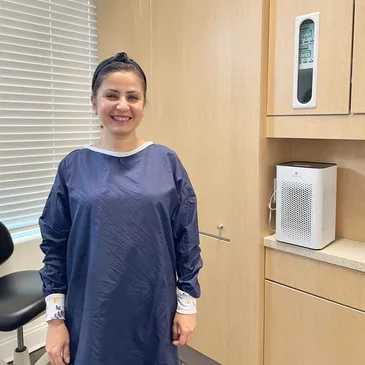 A woman in a hospital gown standing next to a cabinet.