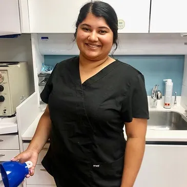 A woman in black shirt holding blue cleaning product.