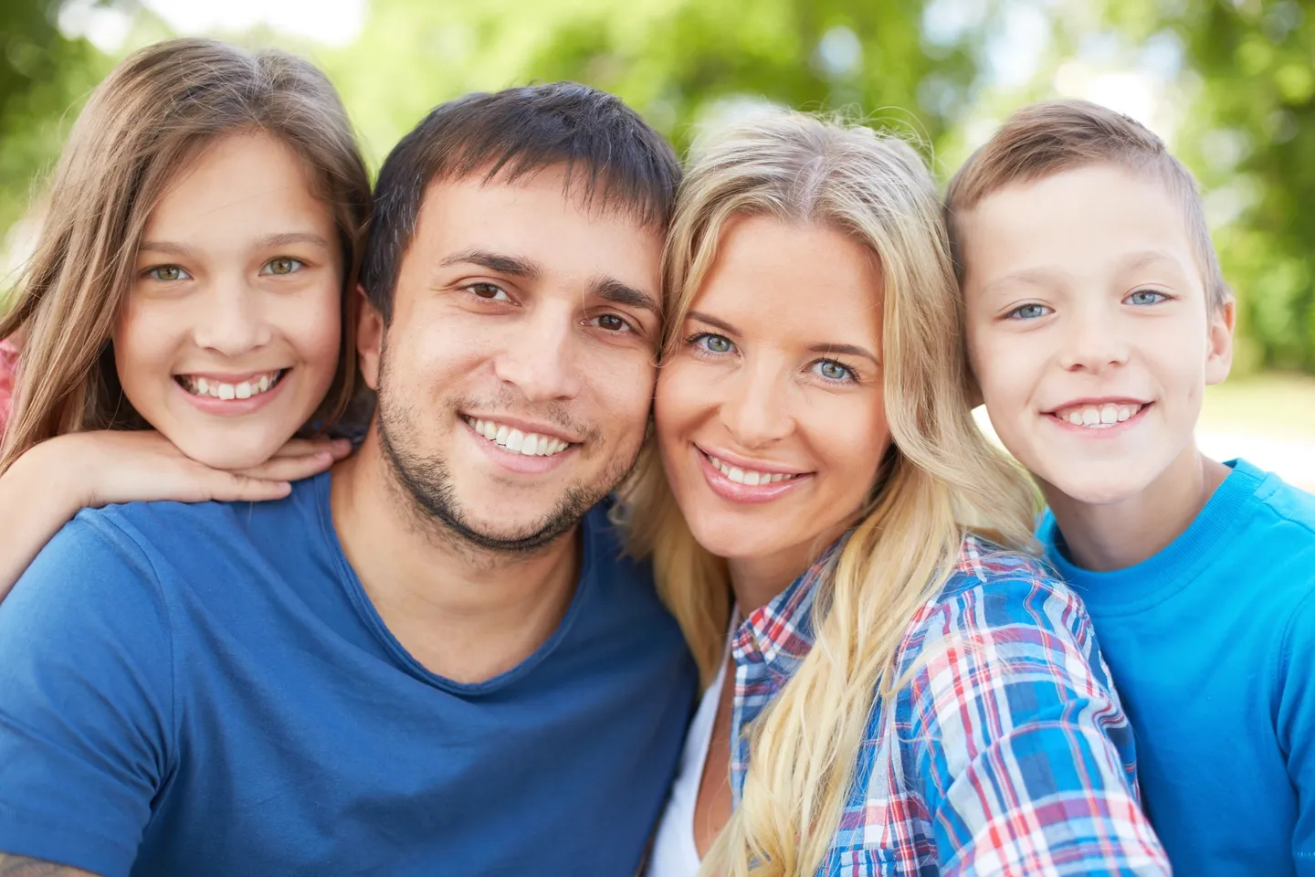 A family posing for the camera in front of trees.